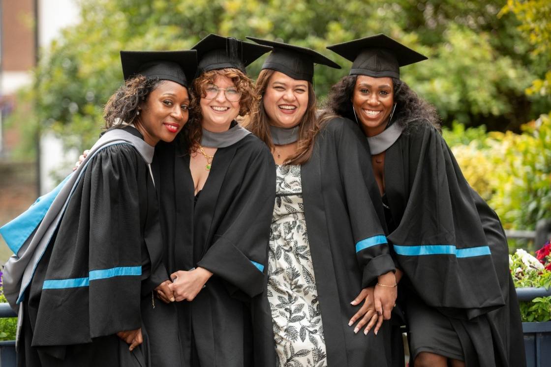 four female graduates in robes and mortarboard hats