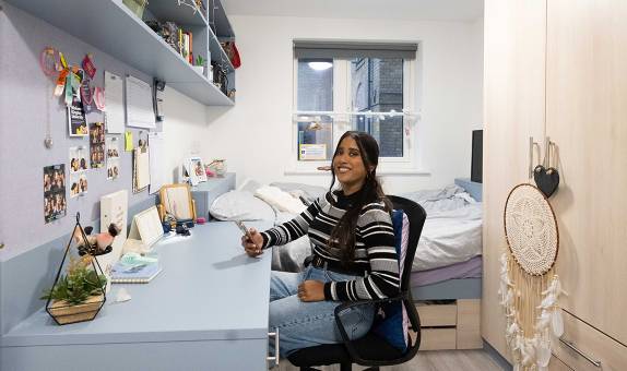 A female student sitting at their desk in the premium non en suite room