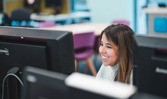 Smiling student studies at laptop