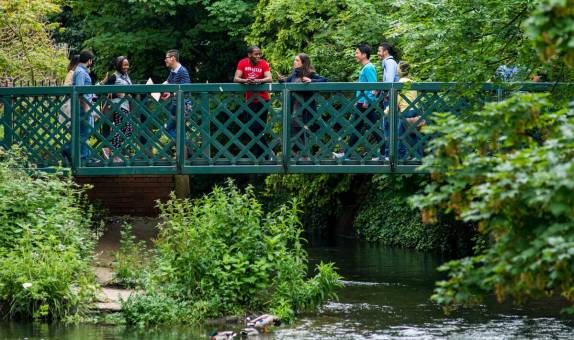 Seven KU students on the bridge above a river surrounded by greenery