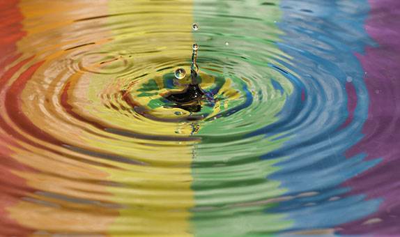 A rainbow flag reflected in water