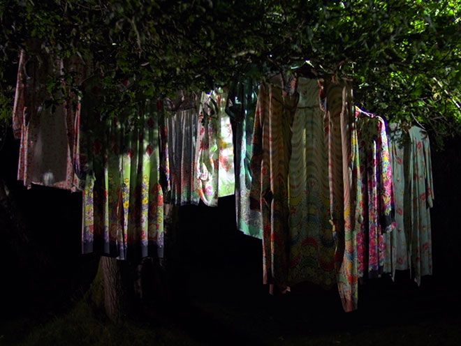 Still of colourful smocks hanging in a tree from Florence Kennard\'s film, Norma\'s Colours.