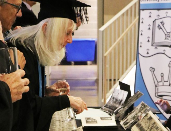 Graduates looking at photos on display at Kingston Archive