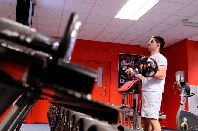 Male student lifting barbell weight in Kingston University fitness centre
