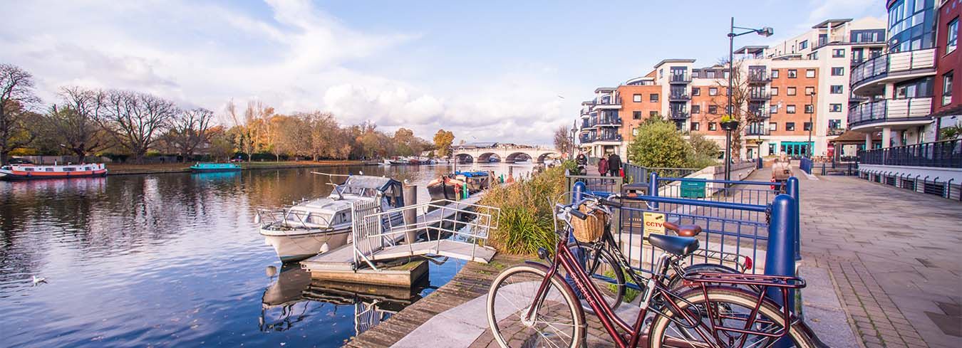 Kingston riverside view showing boats, a park, flats, and a bike in the foreground