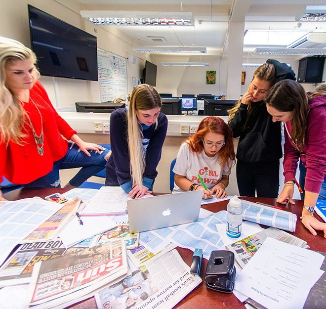 Pictures of journalism students surrounding some newspapers.