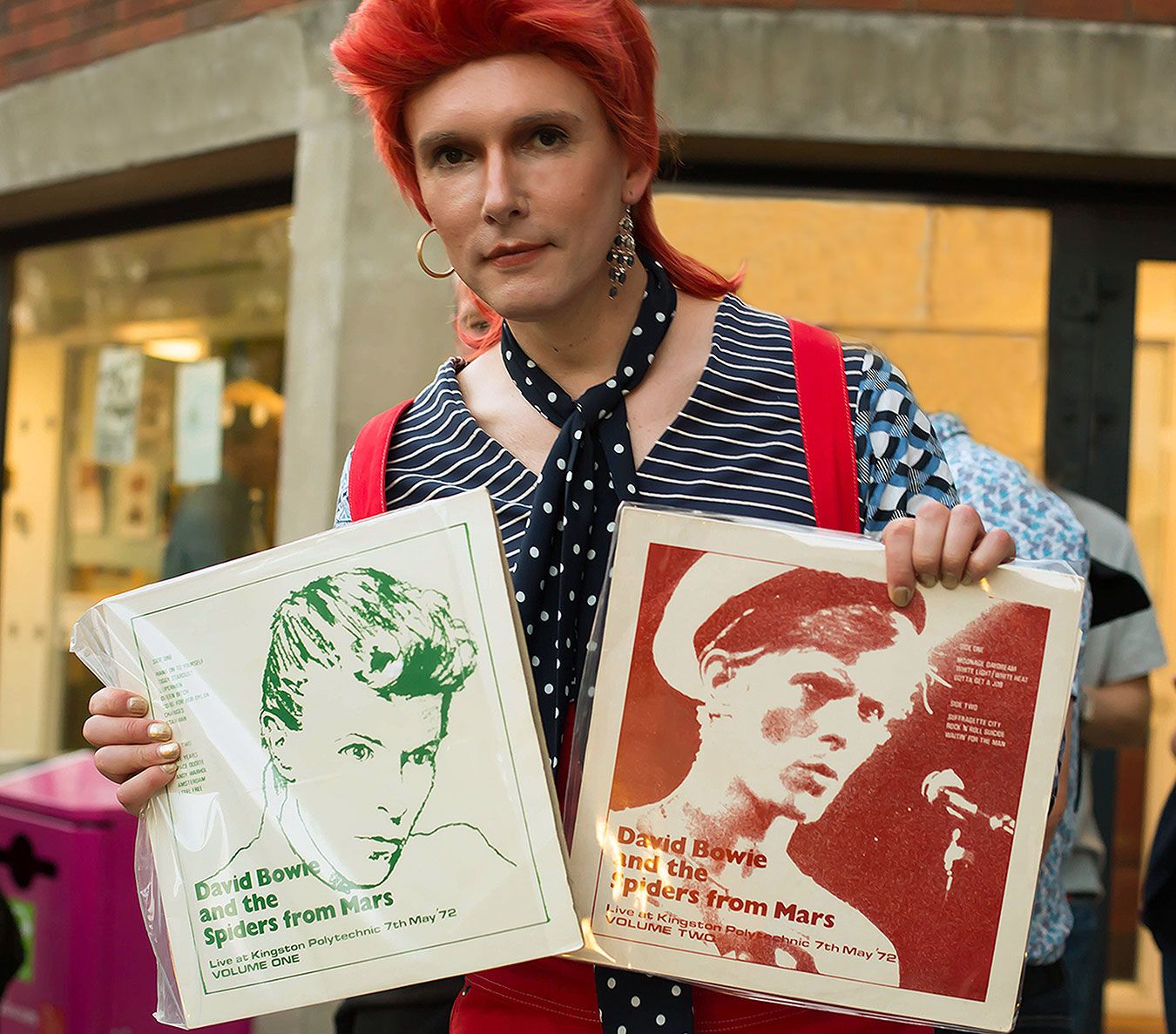 Picture of Professor Will Brooker dressed as Ziggy Stardust holding two bootleg albums from the original Penrhyn Road gig