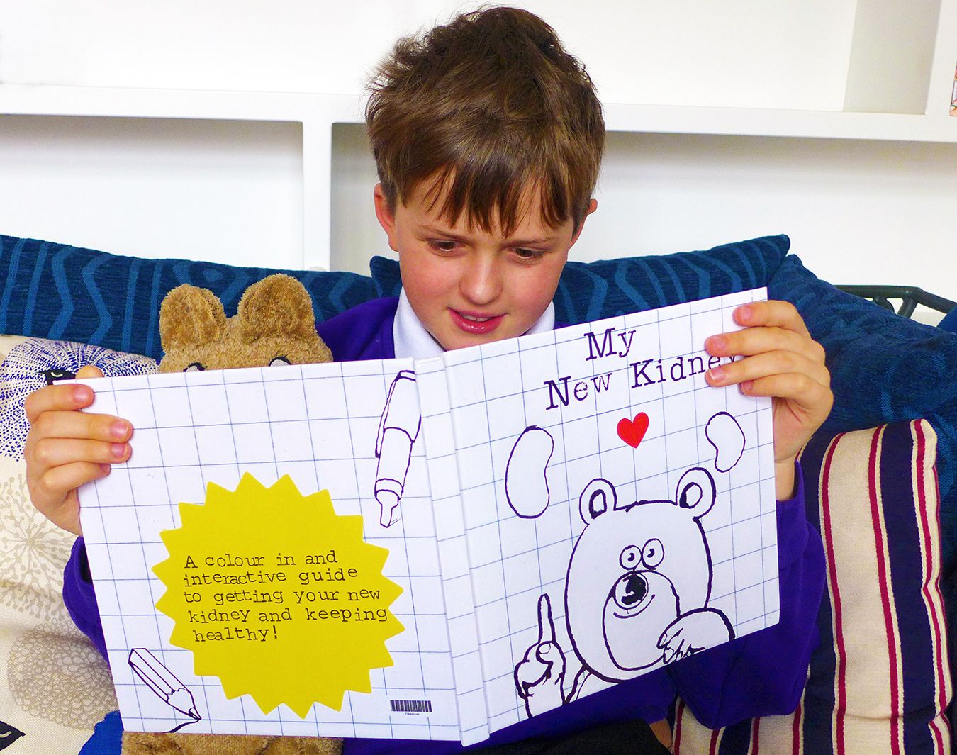 A photo of a young boy holding the My New Kidney book.