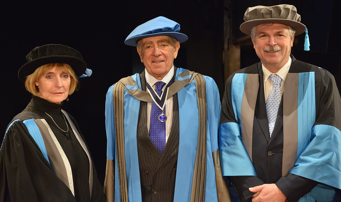 Colonel Godbold stands between Professor Anne Boddington and Professor Ron Tuninga in his graduation robes