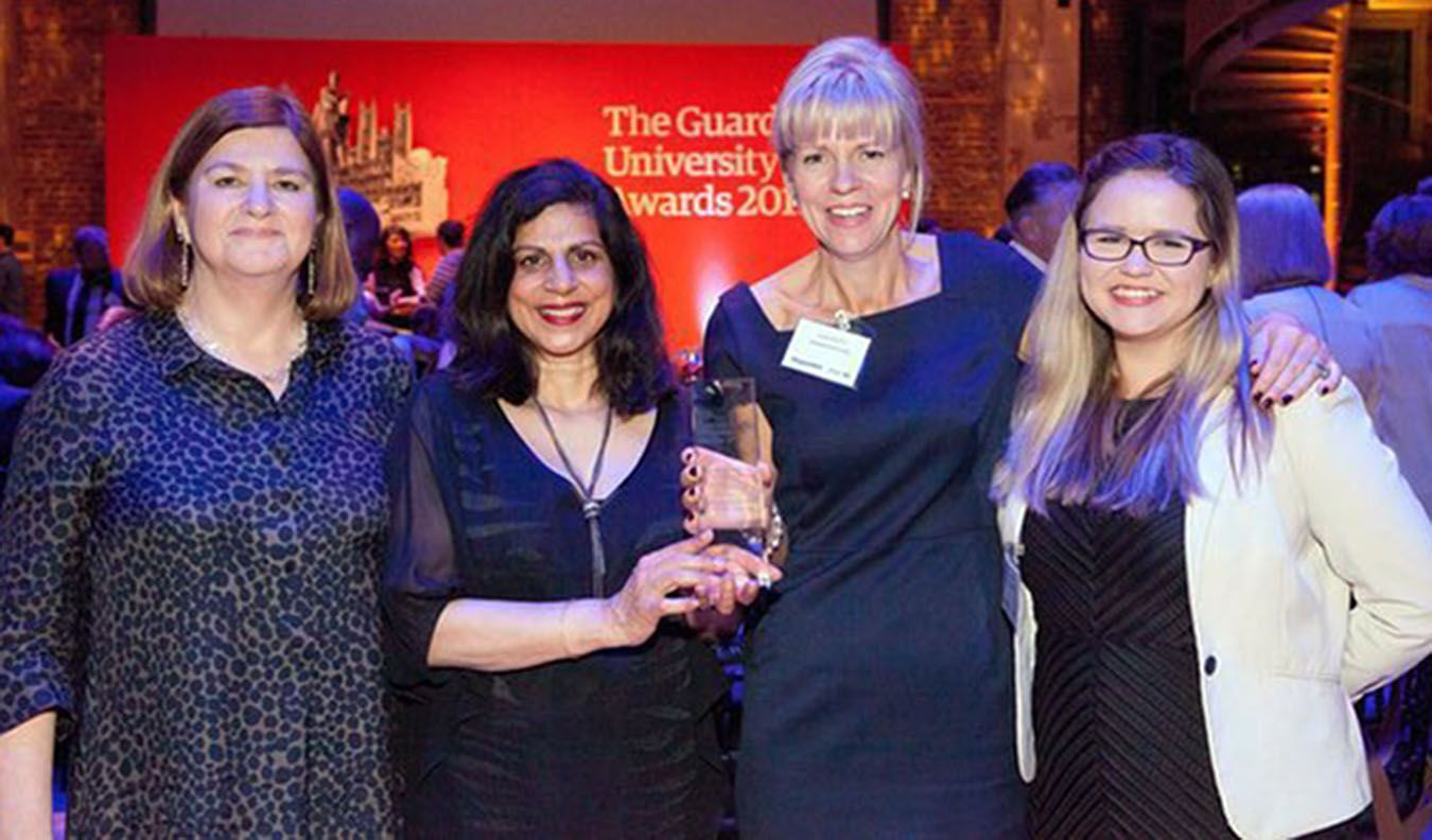 Picture of four ladies with one holding a Guardian University Award trophy.