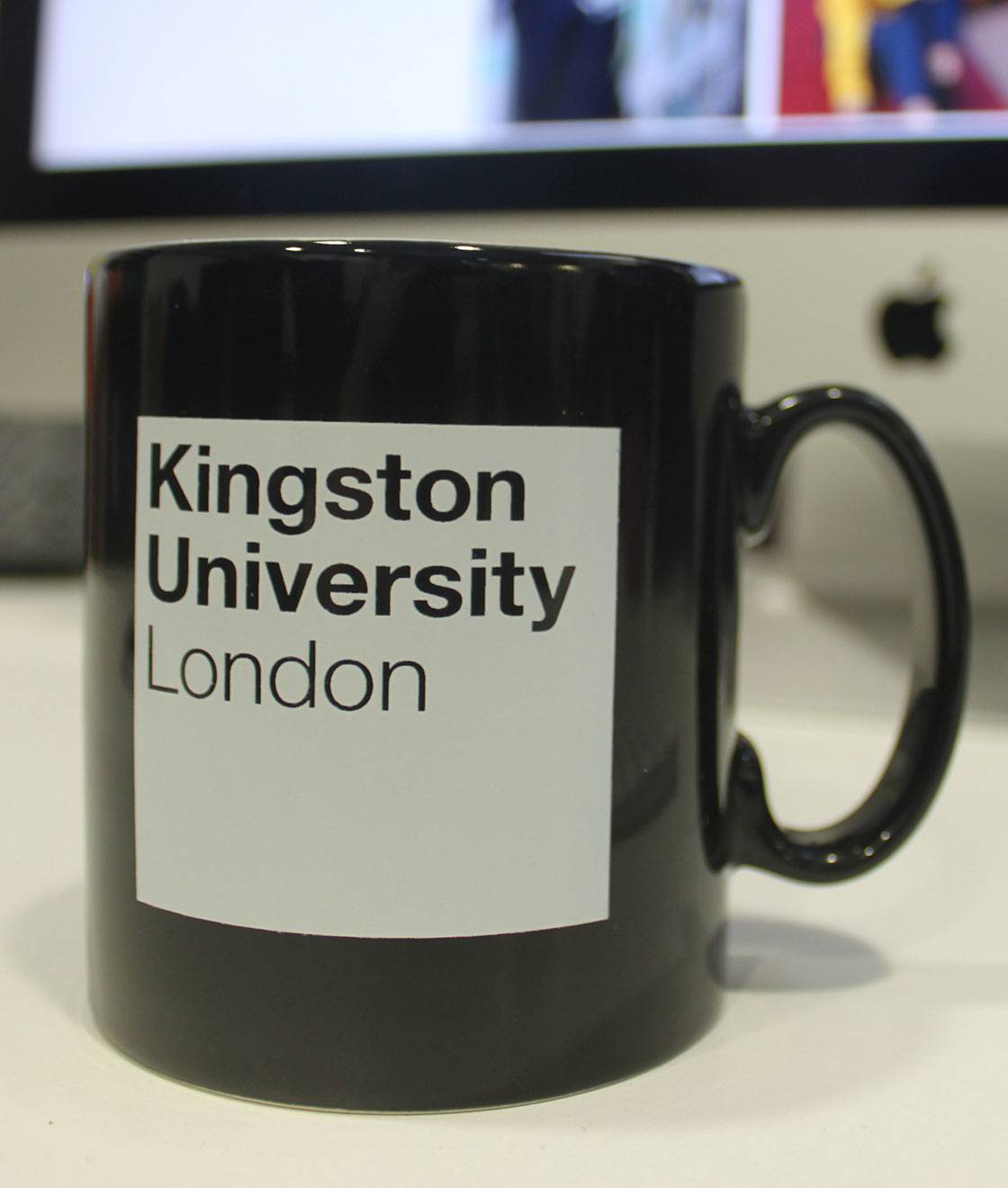 A black mug with a white Kingston University London logo