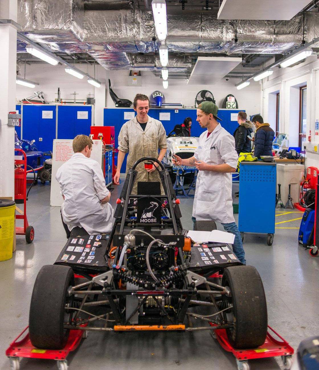 Three engineering students working on a Formula Student car.
