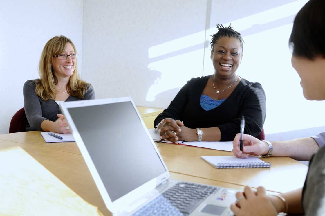 Three women smiling in a business meeting.