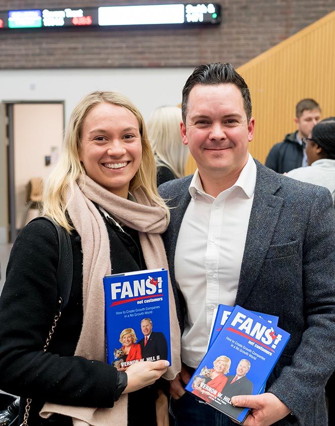 A photo of a man and a woman holding up Vernon Hill\'s book at the Strategy into Practice seminar.