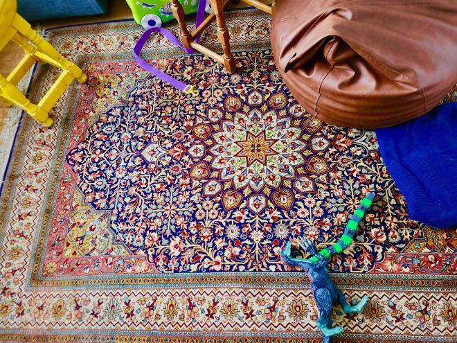 Patterned Persian-style carpet, wooden chairs, toy dinosaur