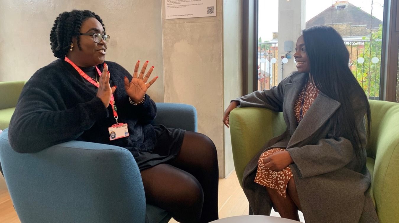 Two women sitting on chairs talking 