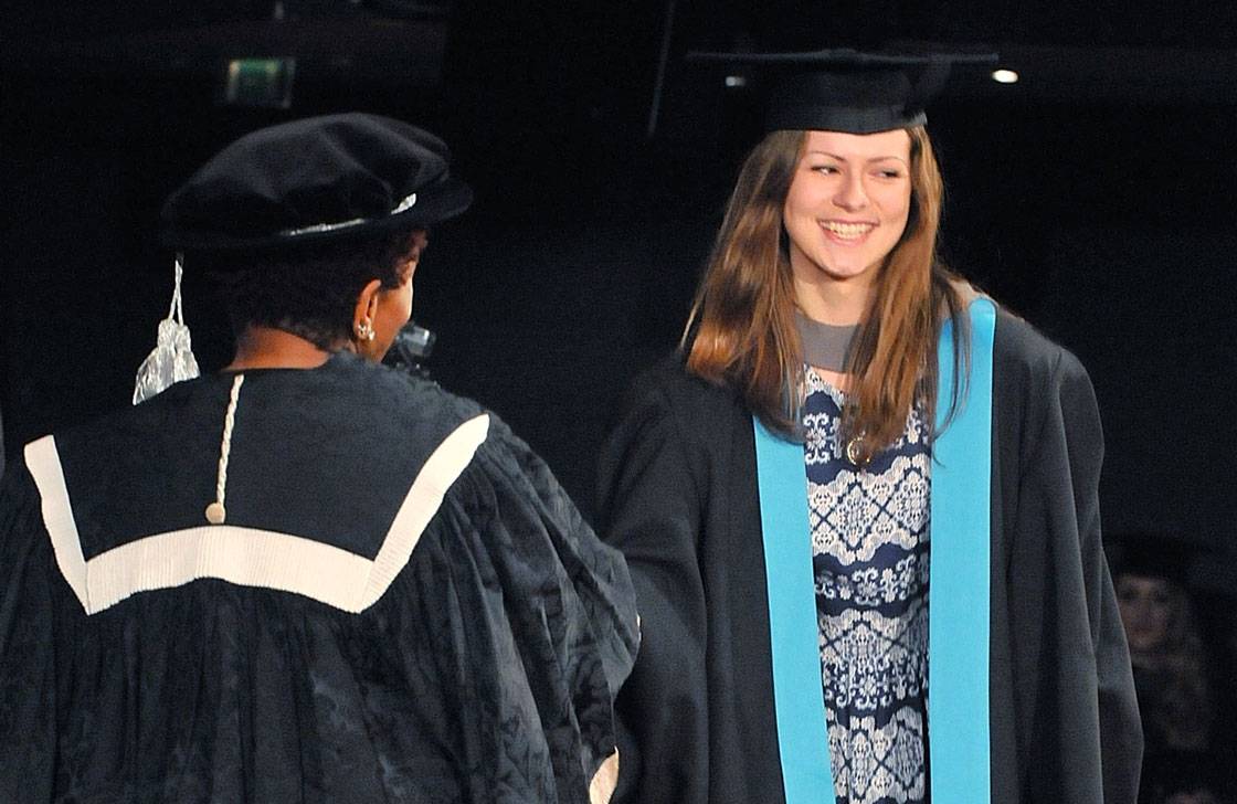 A smiling graduate is receiving her award.