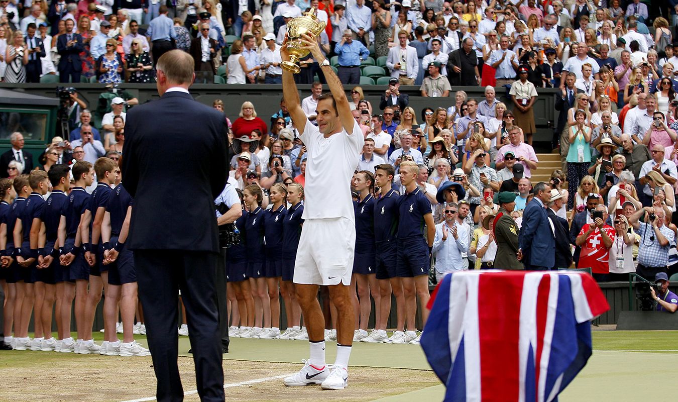 Roger Federer stands with Wimbledon tennis trophy on front of crowd