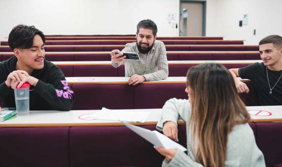 four students chatting in a lecture theatre