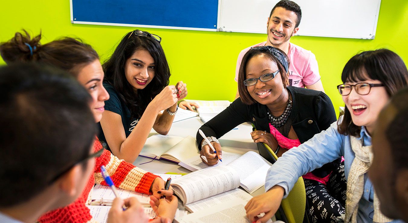 A photo of a number of Kingston University students in a discussion around a table.