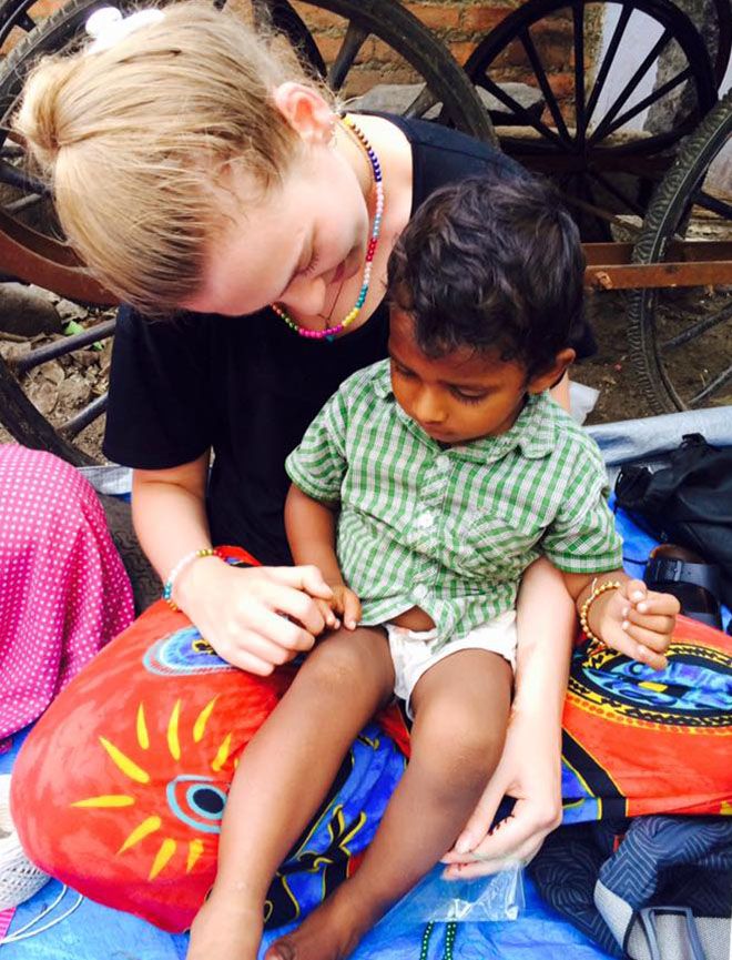 Student volunteer Catherine Green with the young son of one of the families living in a Chennai beach slum.