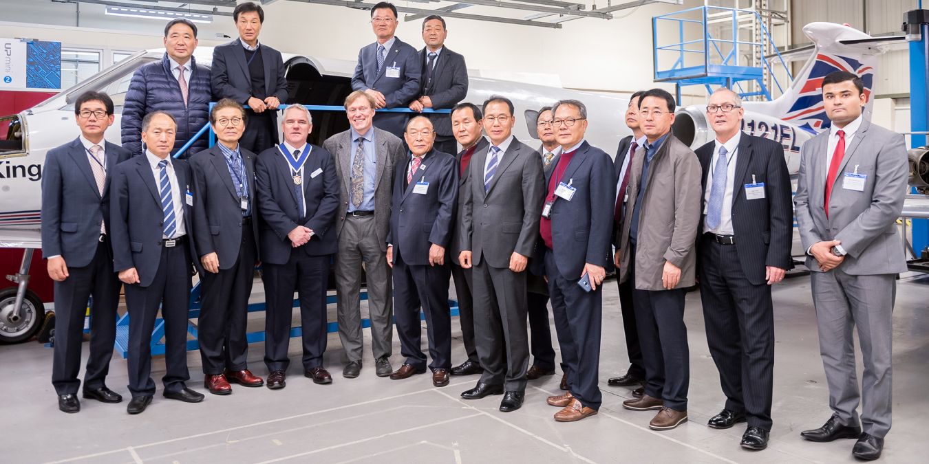 Men in suits standing in front of an aeroplane