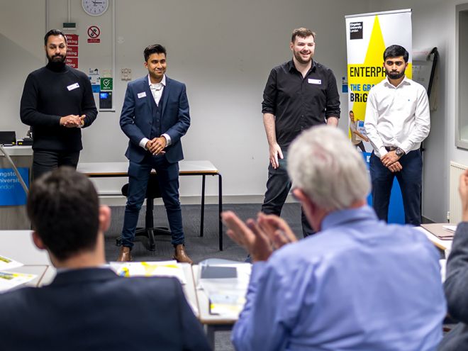 Four male students pitch their idea to a panel of judges