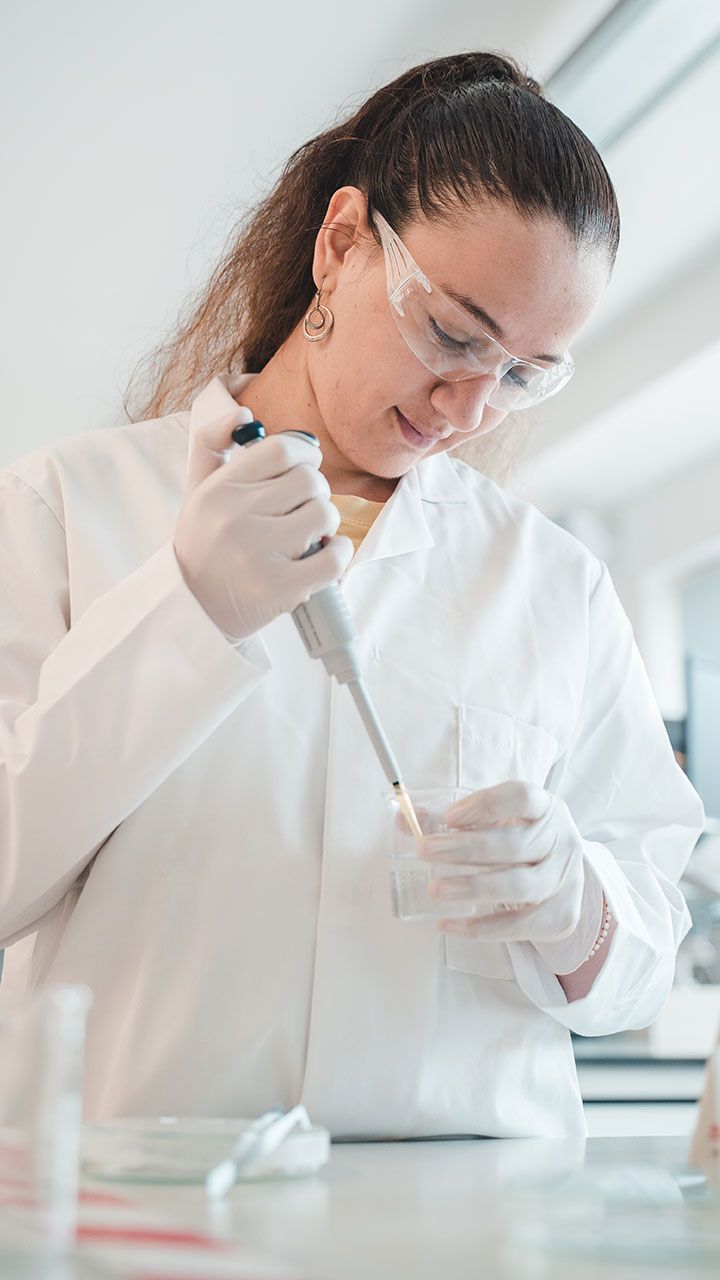 Female student in lab coat and goggles performing an experiment
