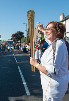 Margaret Loveridge prepares to receive the flame from Reda Vida Gani in front of hundreds of spectators on Penrhyn Road.